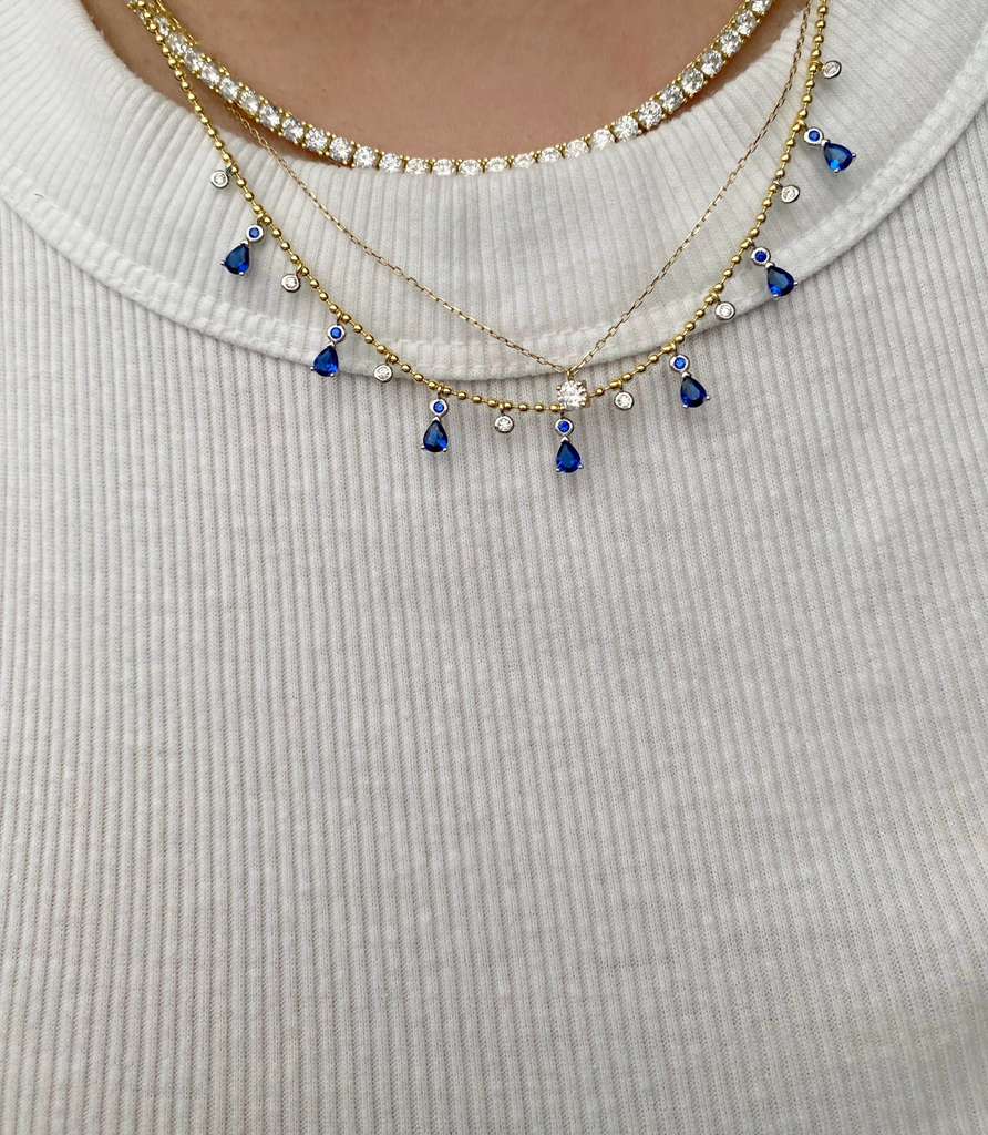 Playful sparkle, timeless charm.
This dainty teardrop necklace features zirconia drops in vibrant colors, delicately set along a beaded 925 sterling silver chain with 18k gold plating.
Its 16” + 2” extender makes it perfect for layering or wearing solo.

Available in multiple shades — clear, sapphire blue, ruby pink, and emerald green — so you can mix, match, and glow in your own way

