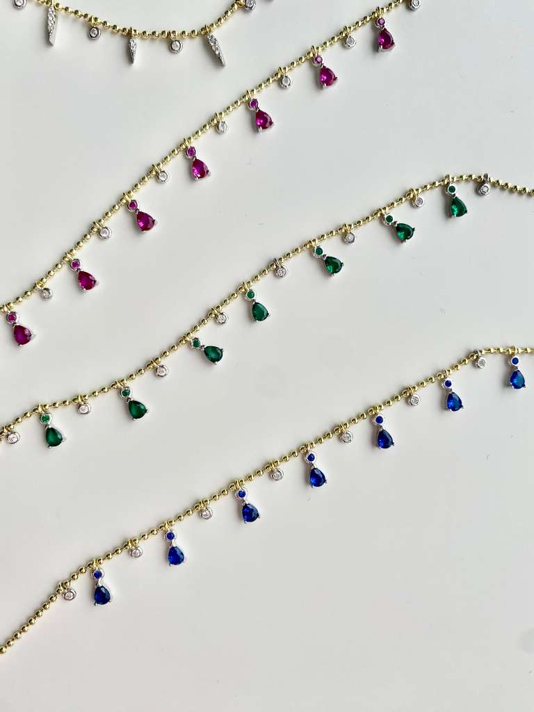 Playful sparkle, timeless charm.
This dainty teardrop necklace features zirconia drops in vibrant colors, delicately set along a beaded 925 sterling silver chain with 18k gold plating.
Its 16” + 2” extender makes it perfect for layering or wearing solo.

Available in multiple shades — clear, sapphire blue, ruby pink, and emerald green — so you can mix, match, and glow in your own way
